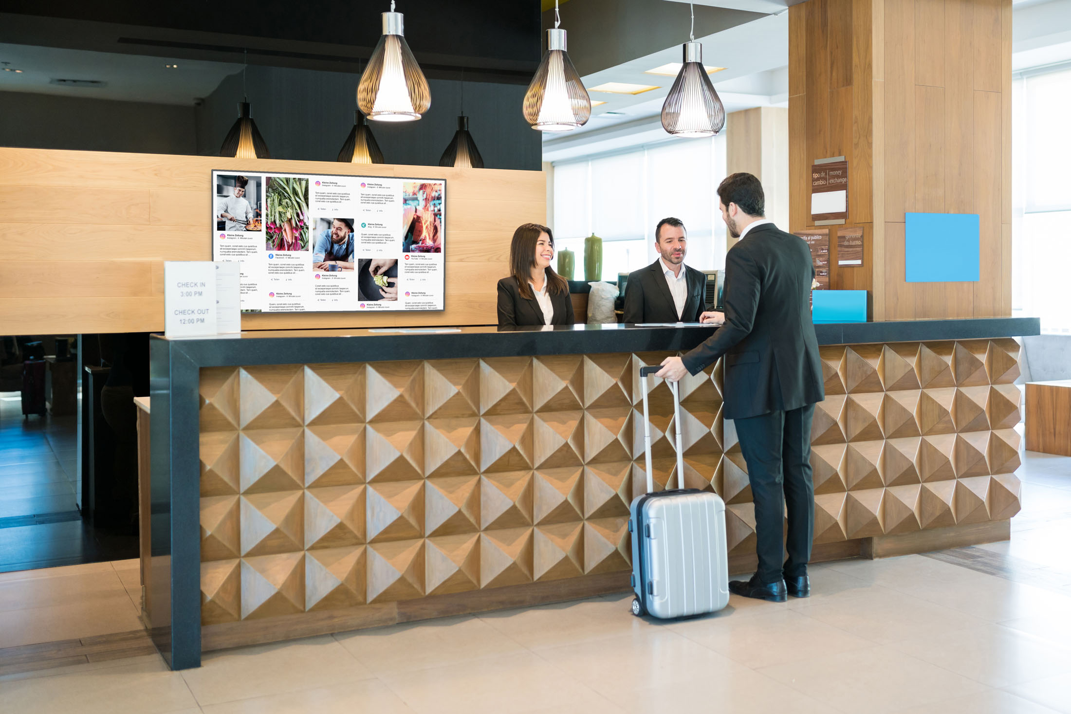 Businessman making booking at front desk with Latin receptionists in hotel lobby